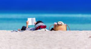 person reading a book on the beach for summer reading and books